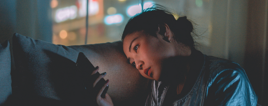 A woman staring at her phone - struggling to get to sleep