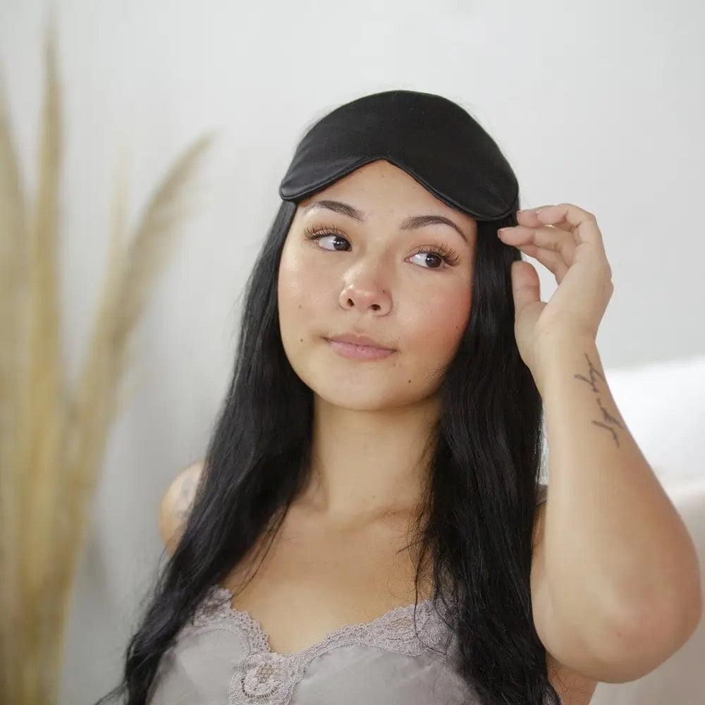 Woman with black hair wearing a black silk eye mask