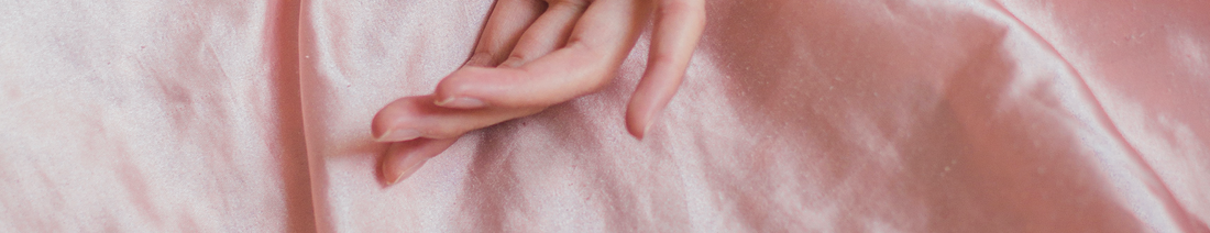 Woman's hand on pink silk sheet