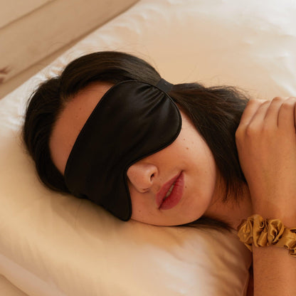 Woman in bed with a black mulberry silk eye mask over her eyes