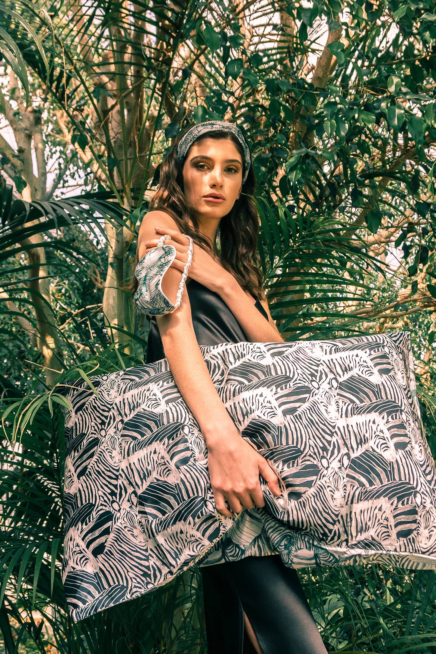 Model holding a zebra Print 100% Mulberry Silk Eye Mask and carrying a pillow