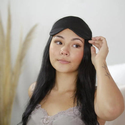 Woman with black hair wearing a black silk eye mask
